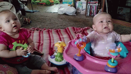 two babies in playpens with toys on the floor
