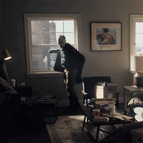 a man is standing in a living room by a window