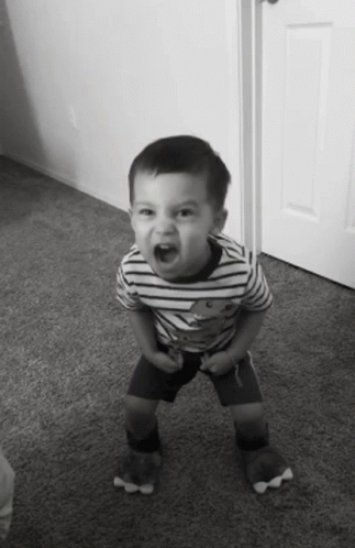 a baby in a striped shirt laughing by a doorway