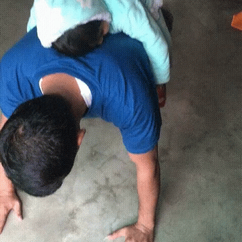 a boy in an orange shirt and blue pants, grabbing his arms over his head