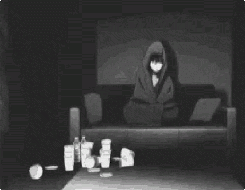 a hooded person sitting on top of a couch with several candles on the ground