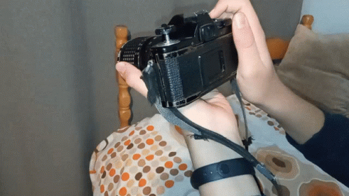 someone in gloves holding a camera up to their face