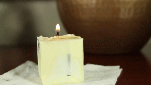 the candle is lit on a napkin with a blue vase in the background