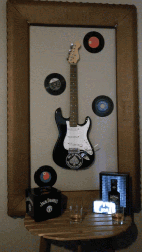 a guitar sitting next to some records in a frame