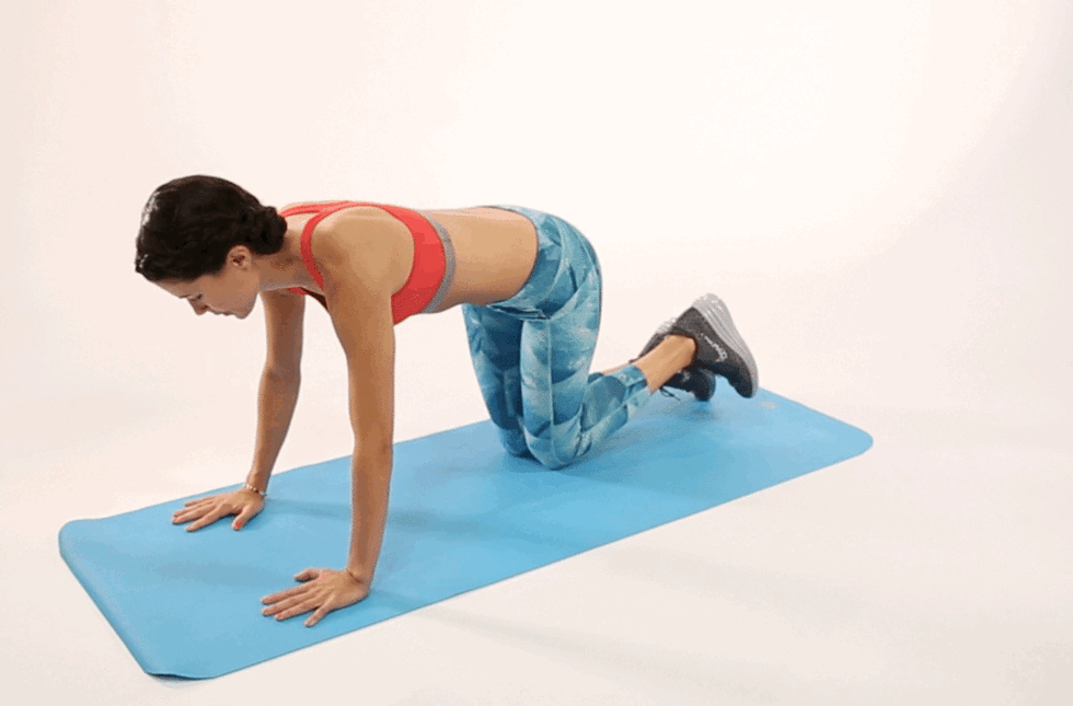a woman performs a h up exercise on a mat