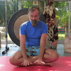a man sitting on top of a yoga mat in front of windows