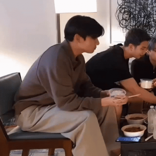 a group of men sit together eating food and talking