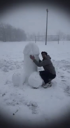 a man is standing in the snow next to a snowman