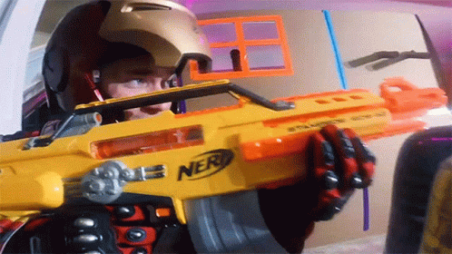 a person holding a futuristic toy gun with his face obscured by a blue helmet