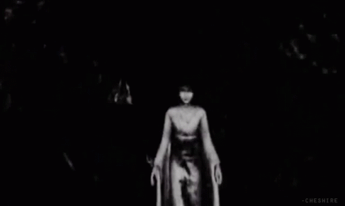 a woman standing in a dark cave alone