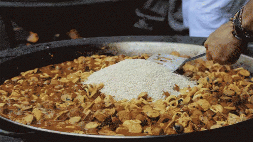a person stirs food into a frying pan