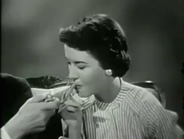 a woman being fed a slice of pizza