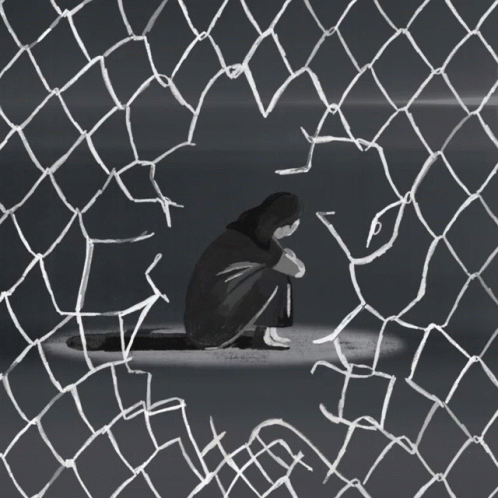 a boy sits alone in a mesh enclosure