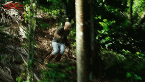 a man is jumping off a tree in a jungle