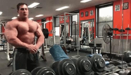 a man stands in a gym with a dumbbell