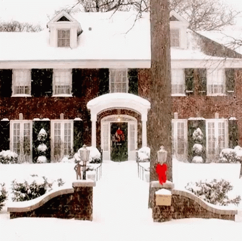 a large brick home with black shutters and snow on the roof