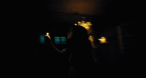 a woman is standing in the dark holding a cell phone