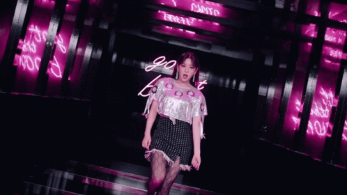 a young woman walking down a runway in front of purple lights