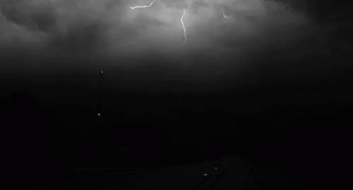 a black and white po of lightning over some hills
