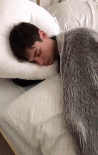 a young person sleeping in a bed that is made of white material