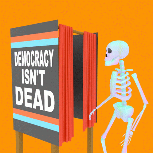 a skeleton sitting beside a sign that says democracy isn't dead