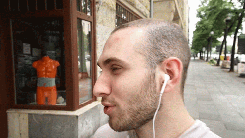 a man with earbuds on, looking at a window