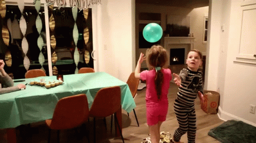 two s are playing with balloons at the table