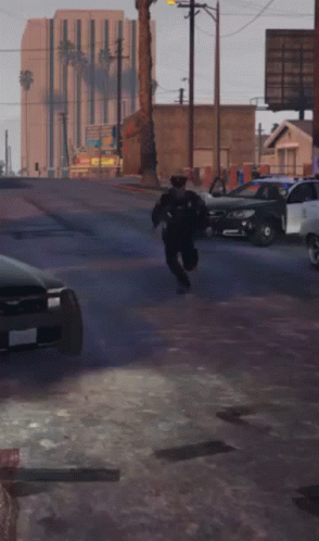 a cop running in a lot next to parked cars