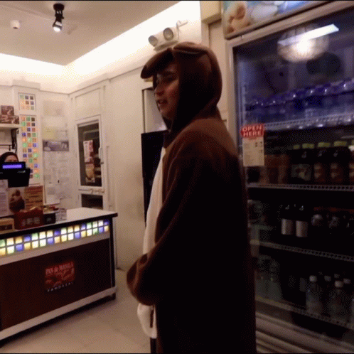 a man with a hood in a store with soda machines
