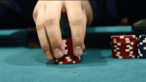 a hand in gloves is reaching for two stacks of poker chips