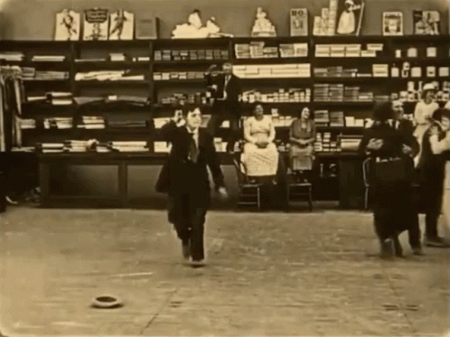 two people walking through a shop in an old picture