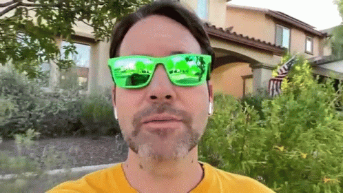 a guy wearing sunglasses and a green reflection in his eyes