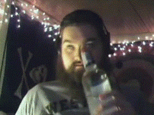 man holding up a beer bottle in a room decorated with lights