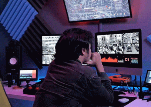 man sits at computer desk staring at monitors