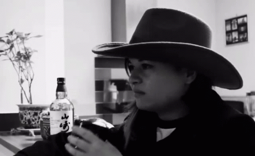 a woman wearing a cowboy hat holding a bottle