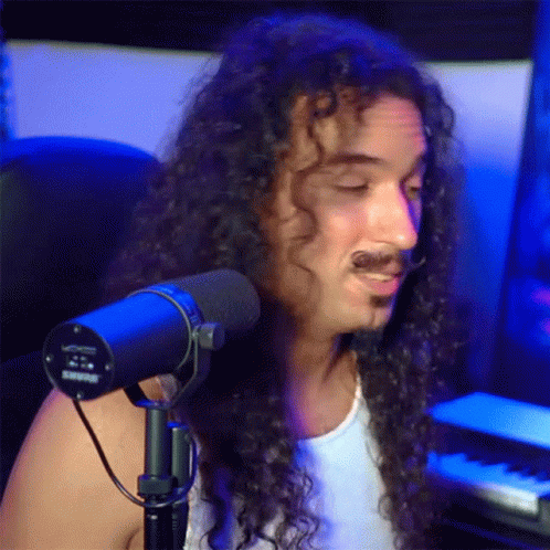 man with long hair on singing into a microphone