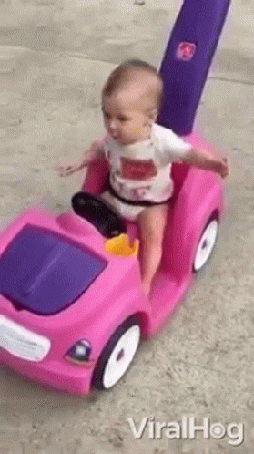 an image of a baby riding a small toy car