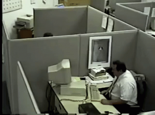 an office cubicle with a man on the computer
