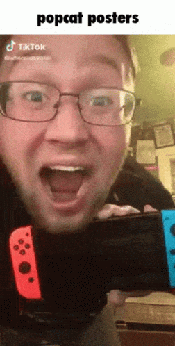 a man in glasses has his mouth open and a nintendo wii remote in front of him