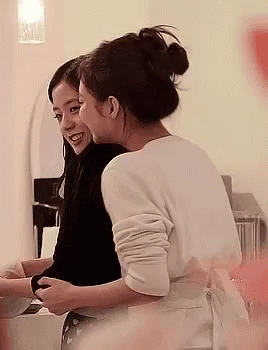 two women laugh as they brush their teeth