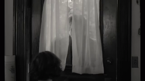a woman standing in front of a doorway near a curtain