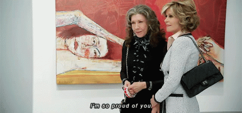 two women talk to each other by a painting