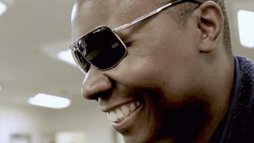 a man in a jacket wearing sunglasses and smiling