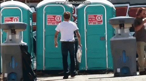 a man is standing in front of several portable toilets