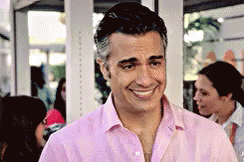 a man smiling for the camera and wearing a pink shirt
