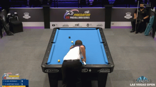 a person standing near a pool table and playing billiard