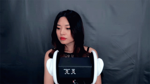 a woman is holding a large replica with headphones on her face