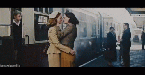 two women are hugging while standing in the train station