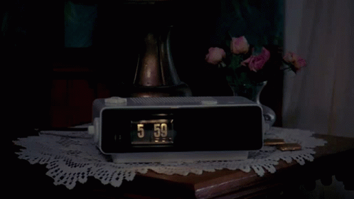 the alarm clock is showing 5 05 in front of a flower arrangement
