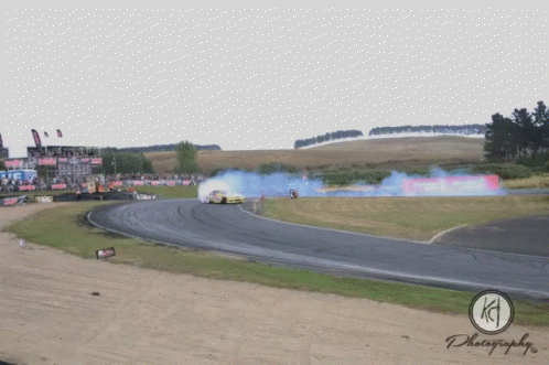 a red and black car kicking up dirt in a race track